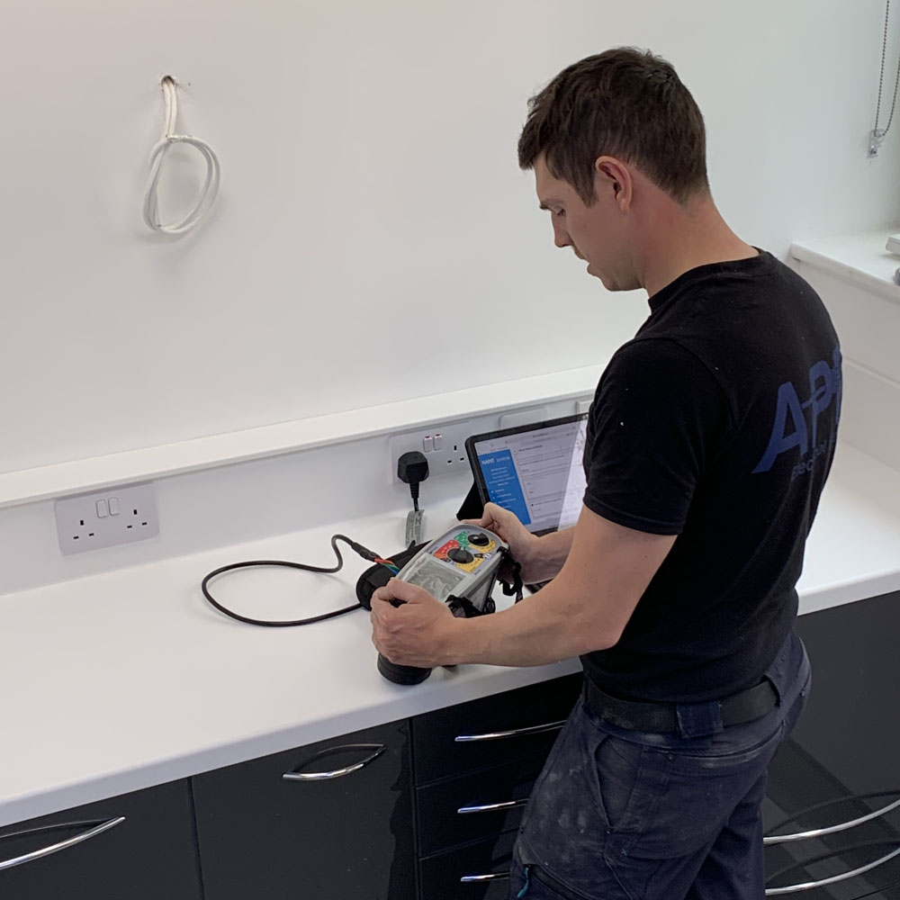 APP Electrical team member Andrew installing and testing plug socket inside of homeowner kitchen.